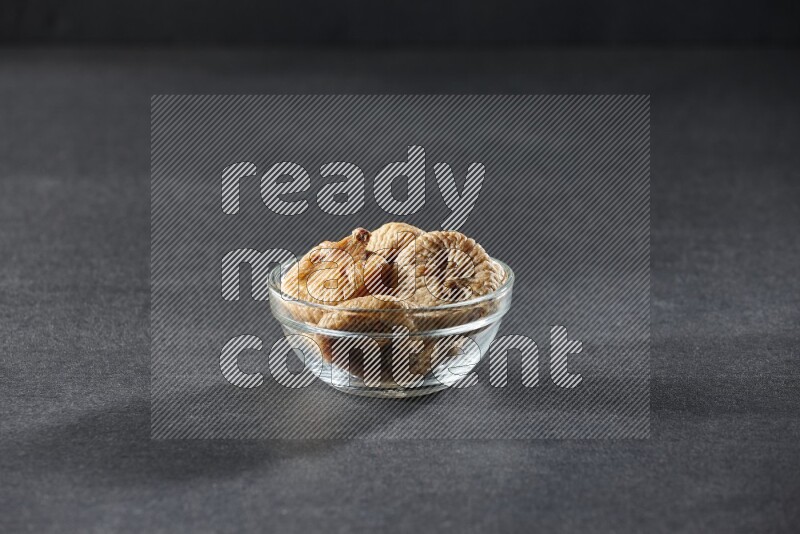 A glass bowl full of dried figs on a black background in different angles