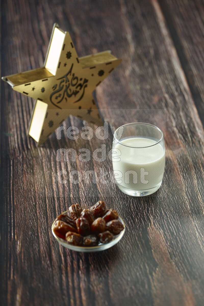 A wooden golden star lantern with different drinks, dates, nuts, prayer beads and quran on brown wooden background