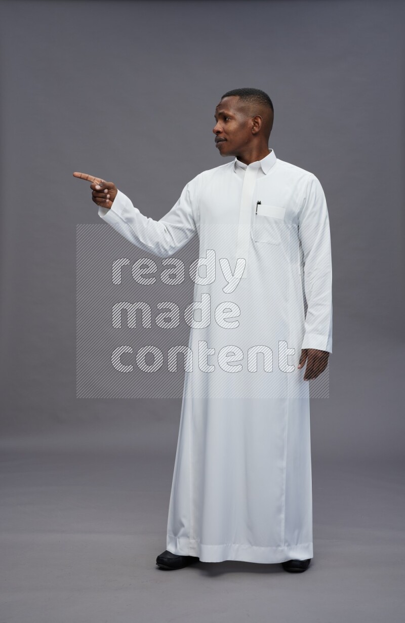 Saudi man wearing thob standing interacting with the camera on gray background