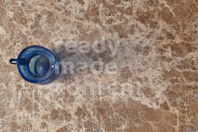 إبريق زجاجي فارغ على خلفية من الرخام البيج