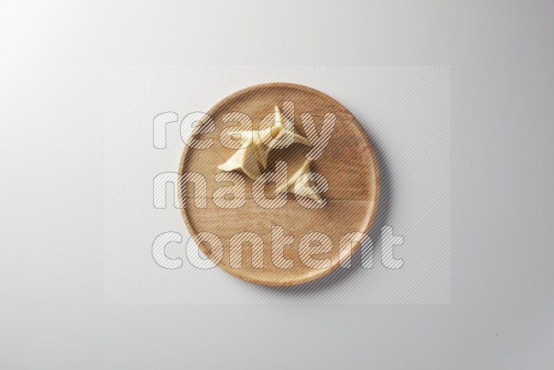 Four Sambosas on a wooden round plate on a white background