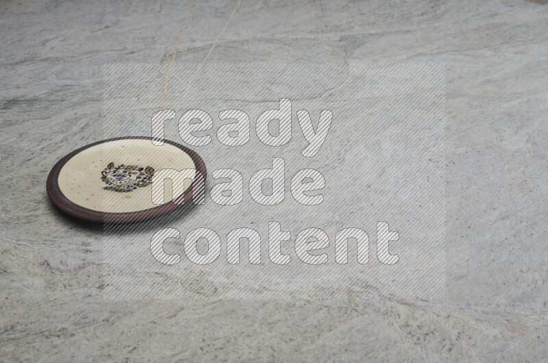 A decorative pottery plate on grey marble background