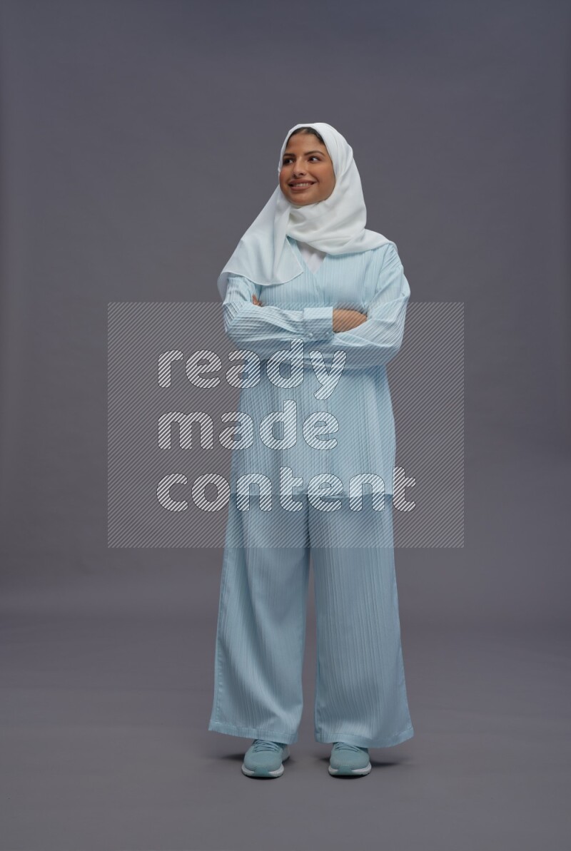 Saudi woman wearing hijab clothes standing with crossed arms on gray background