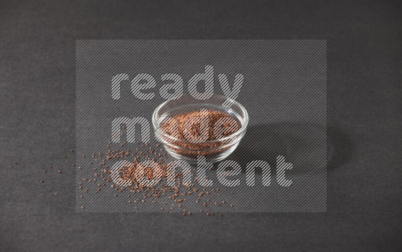 وعاء زجاجي ممتلئ ببذور حب الرشاد محاط بالبذور على أرضية سوداء