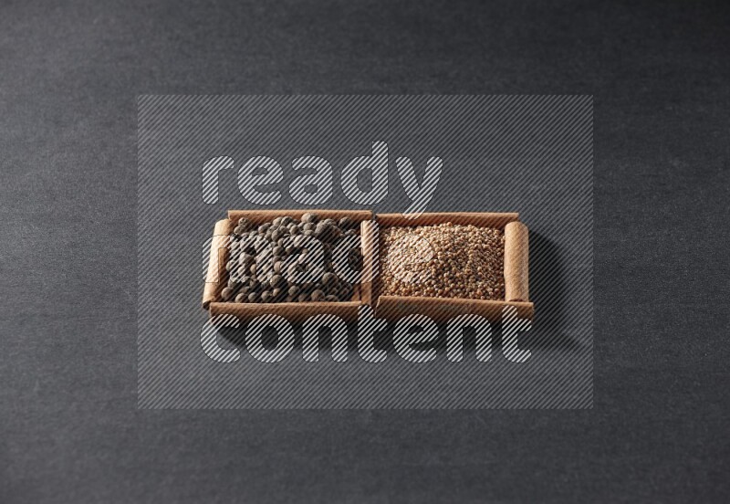 مربعان من أعواد القرفة ممتلئان بحبوب الخردل وحبوب بهار الفلفل الحلو علي خلفية سوداء