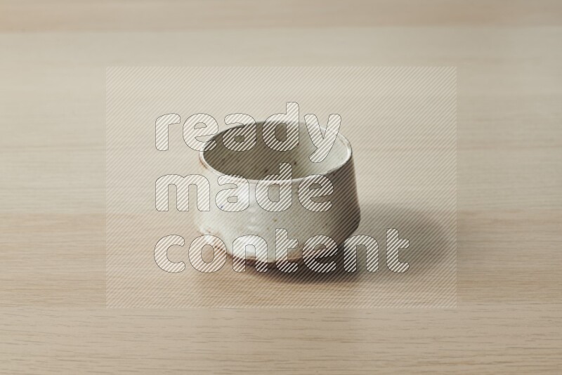 A beige pottery bowl on light wooden background