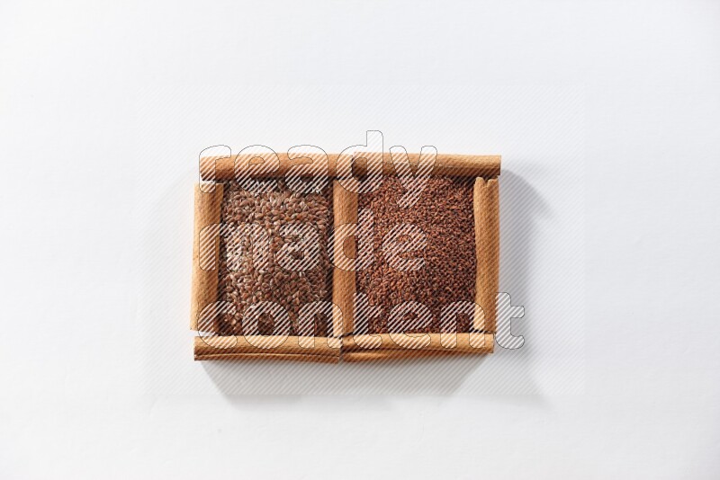 مربعان من أعواد القرفة ممتلئان ببذور الكتان وحب الرشاد علي خلفية بيضاء