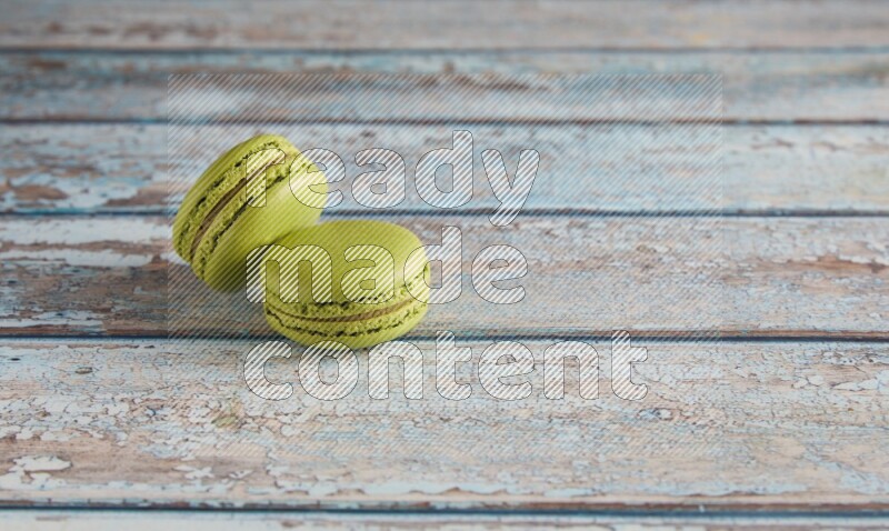45º Shot of two Green Pistachio macarons on light blue wooden background