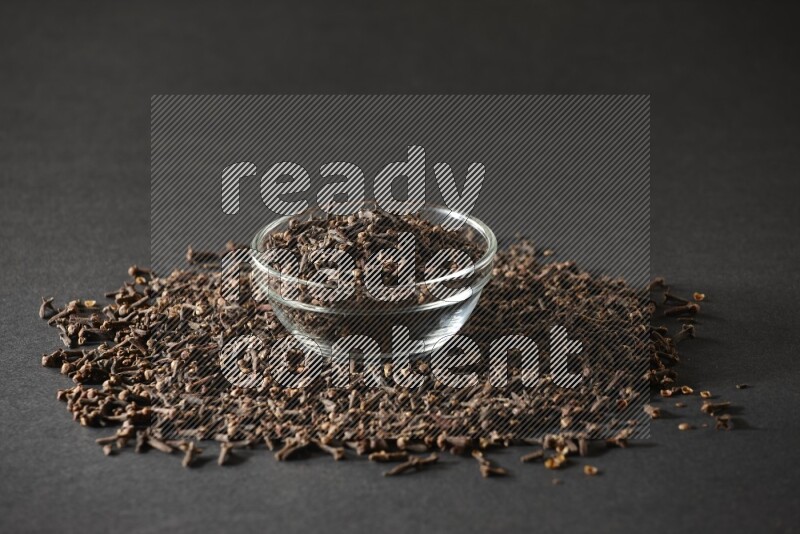 A glass bowl full of cloves on a black flooring
