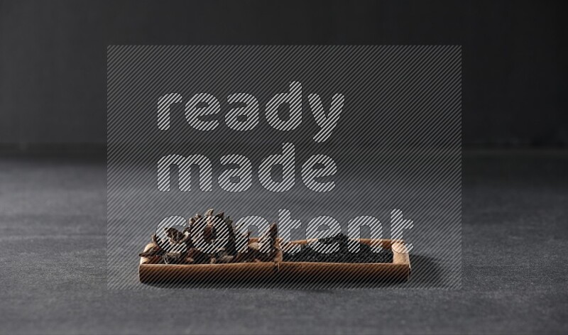 مربعان من أعواد القرفة ممتلئان بحبة البركة السوداء واليانسون النجمي علي خلفية سوداء