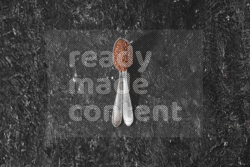 ملعقتان معدنيتان ممتلئتان ببذور حب الرشاد علي خلفية سوداء