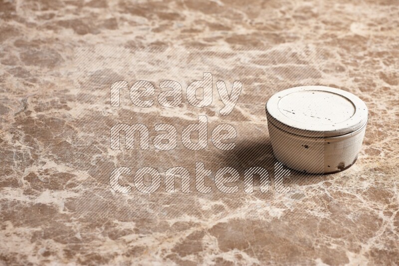 A white pottery bowl on beige marble background