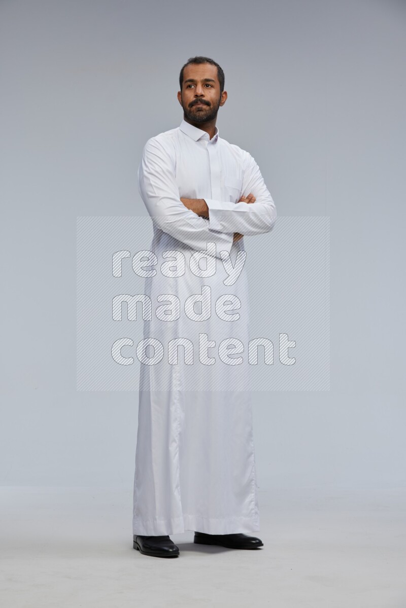 Saudi man wearing Thob standing with crossed arms on Gray background