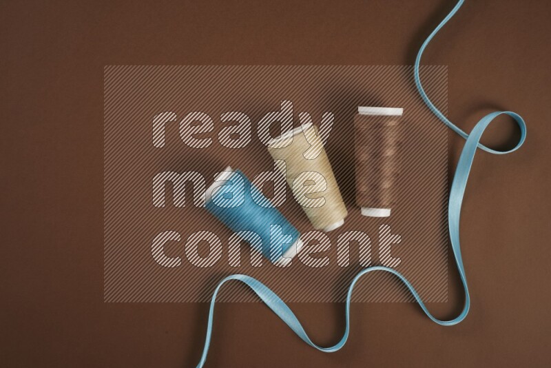 A blue collection of sewing and tailoring tools arranged on a brown background