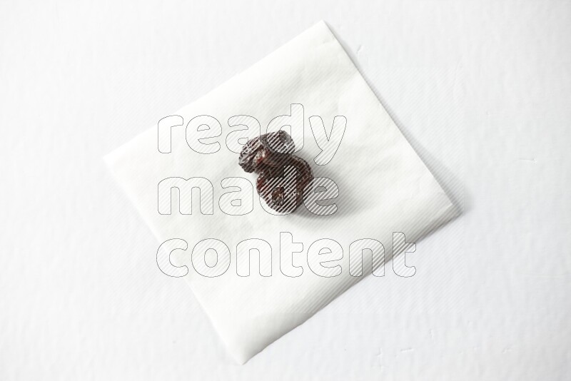 Two dried plums on a piece of paper on a white background in different angles