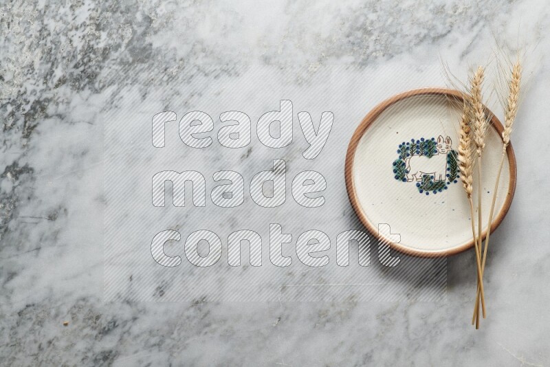 Wheat stalks on decorative pottery plate on grey marble background