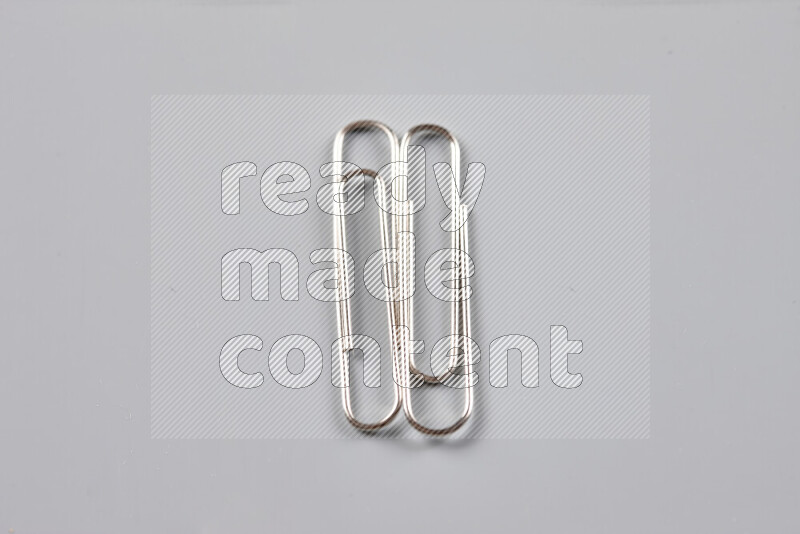 Silver paper clips isolated on a grey background