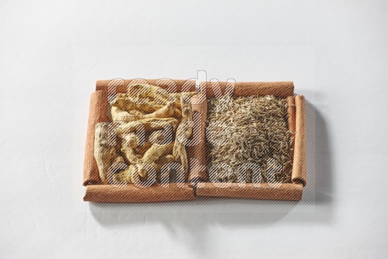 2 squares of cinnamon sticks full of cumin and turmeric fingers on white flooring