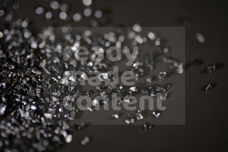 Black shimmering fragments of glass scattered on a black background