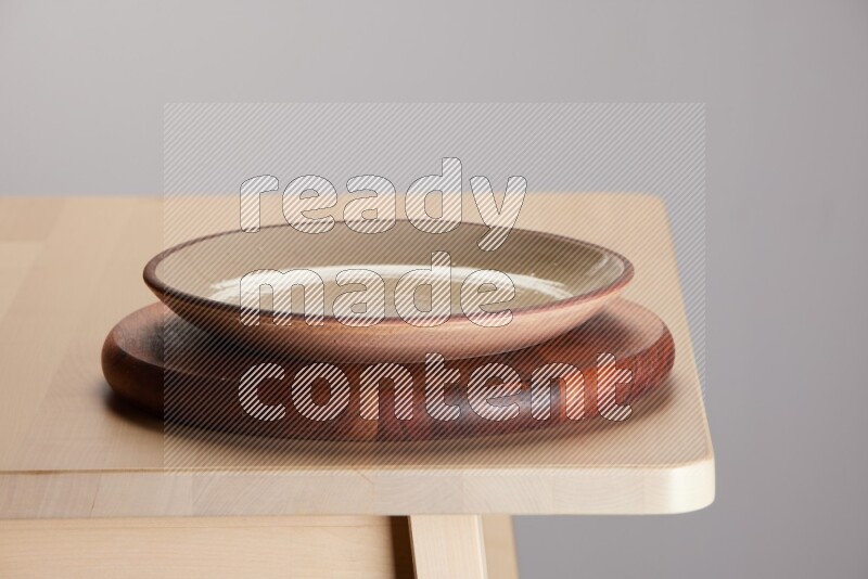 multi-colored pottery Plate placed on a dark colored wooden tray on the edge of wooden table