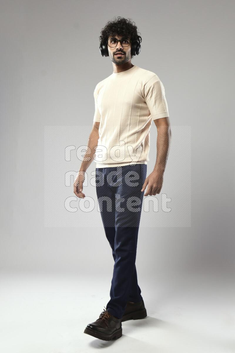 A man wearing casual standing and putting on headphones on white background