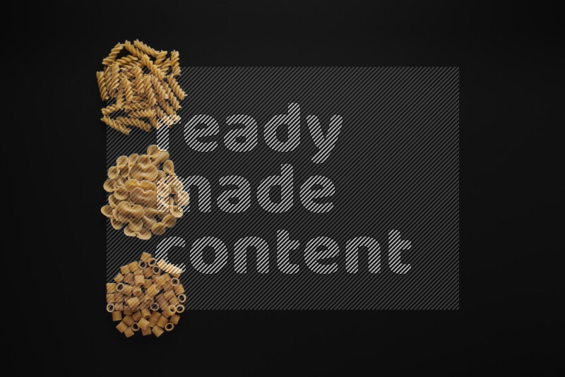 Different pasta types in 3 bunches on black background