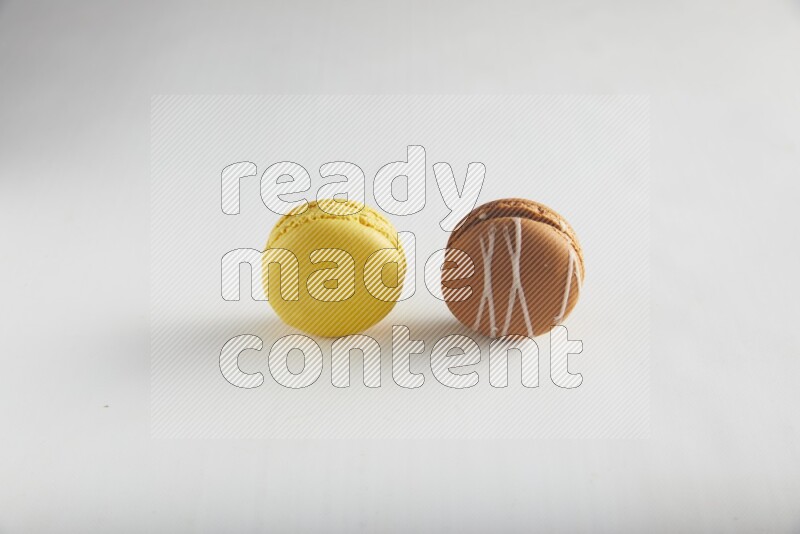 45º Shot of of two assorted Brown Irish Cream, and Yellow Lemon macarons on white background