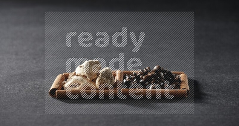 مربعان من أعواد القرفة ممتلئان بحبوب القهوة والزنجبيل المجفف علي خلفية سوداء