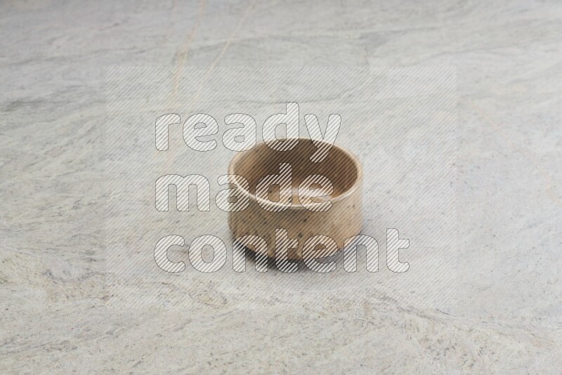 A small beige pottery bowl on grey marble background