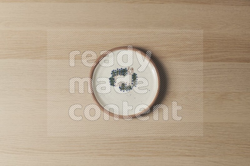 A decorative pottery plate on light wooden background