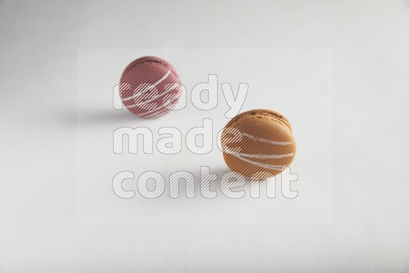 45º Shot of of two assorted Brown Irish Cream, and Red Poppy Flower macarons on white background